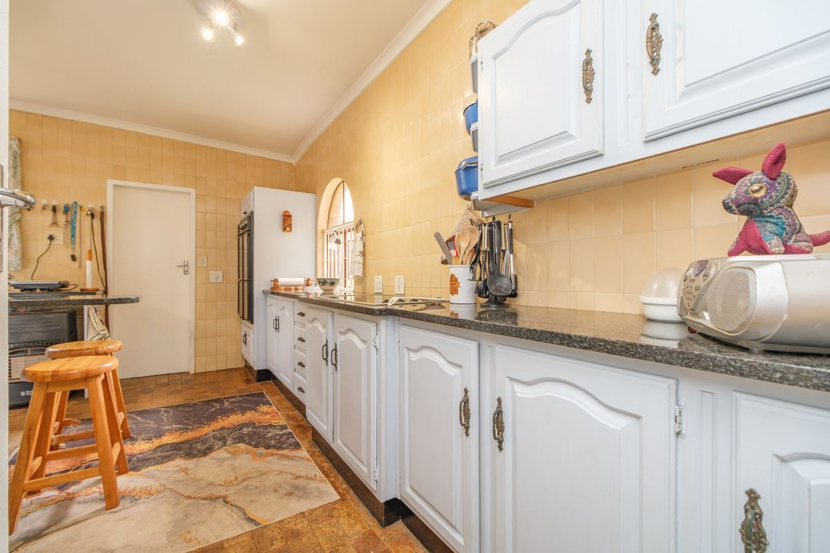 A functional kitchen featuring white cabinetry, granite countertops, and a tiled backsplash, offering a classic layout with built-in cooking appliances.