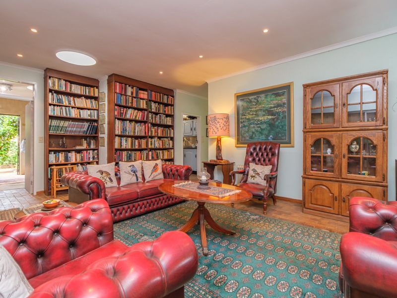 A cozy living room featuring extensive built-in bookshelves, recessed lighting, a skylight, and warm hardwood flooring, creating a classic and inviting atmosphere.
