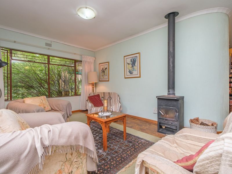 A cozy living room featuring a freestanding fireplace, large windows with garden views, and classic coving details.