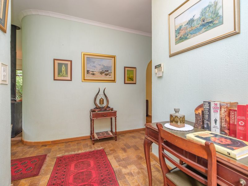 A welcoming hallway featuring classic parquet flooring, a distinctive curved wall, and a cozy wood-burning stove visible in the adjacent space.