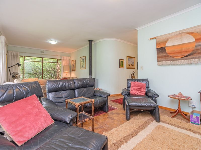 Spacious living room featuring classic parquet flooring, a central freestanding fireplace, and large windows providing natural light.