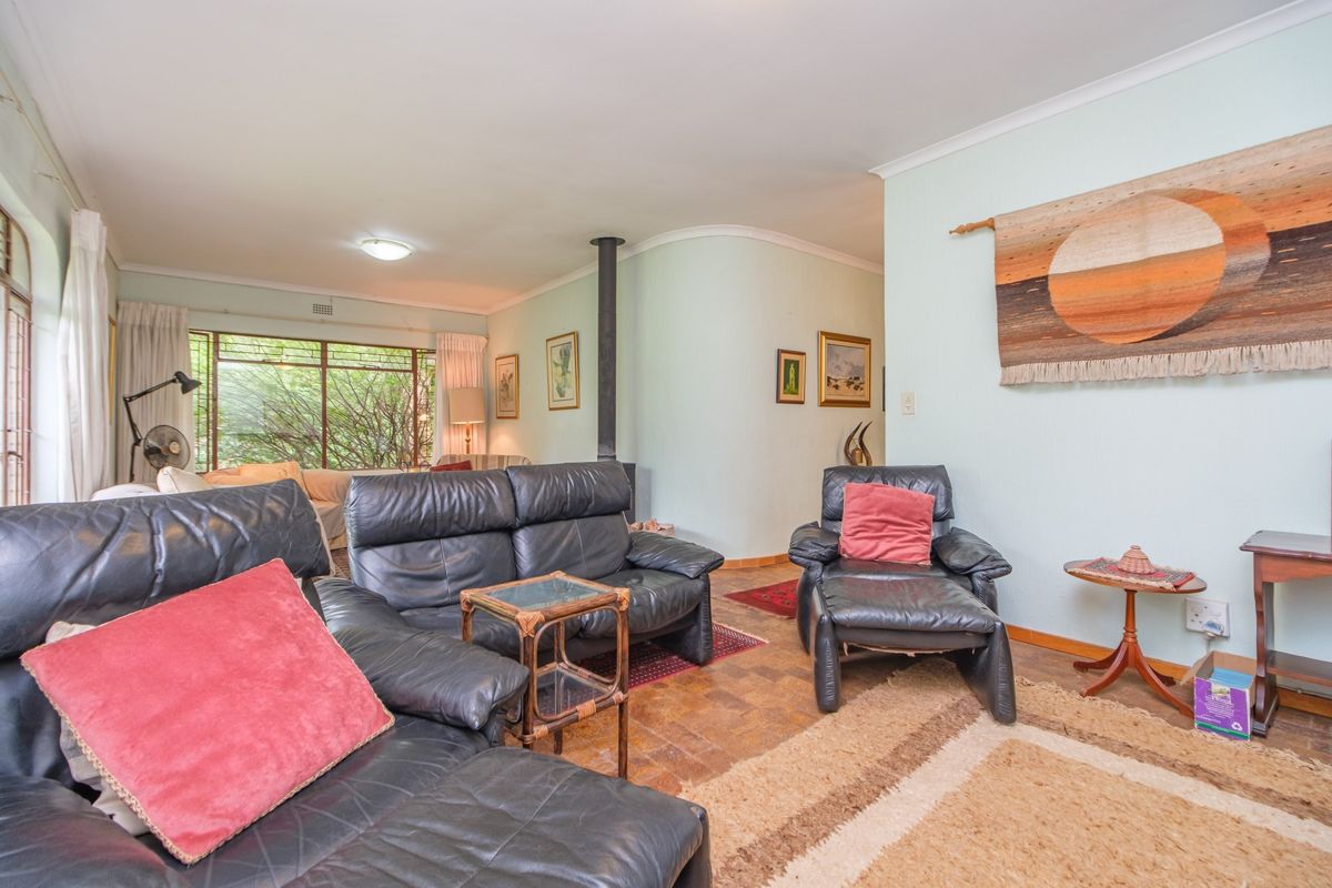 Spacious living room featuring classic parquet flooring, a central freestanding fireplace, and large windows providing natural light.