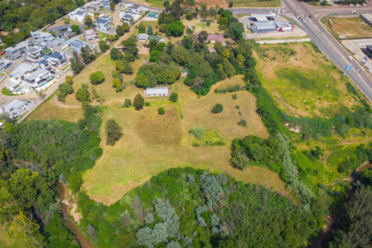 Aerial view of a large, expansive small holding property featuring mature trees, open grazing land, and river frontage in a semi-urban setting.