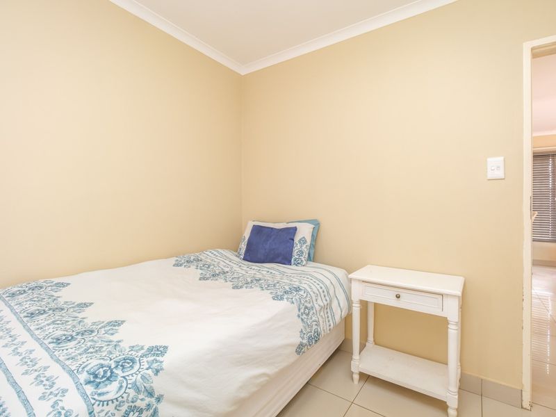 A compact bedroom featuring neutral wall paint, tiled flooring, and coved ceiling detailing, providing a clean and functional living space.