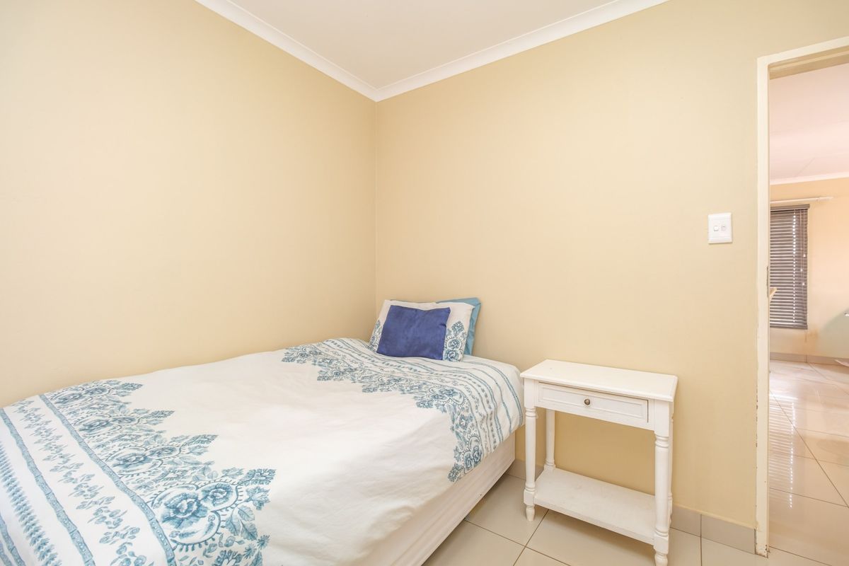 A compact bedroom featuring neutral wall paint, tiled flooring, and coved ceiling detailing, providing a clean and functional living space.