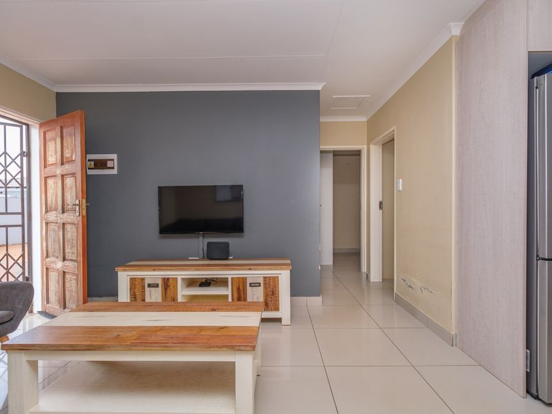 Living room featuring tiled flooring, a feature wall, and direct access to an exterior security gate.