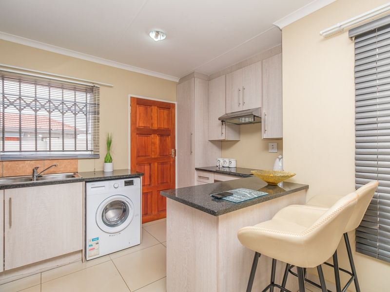 A well-maintained kitchen featuring light wood cabinetry, granite countertops, a breakfast bar, and a built-in extractor fan with tiled flooring.