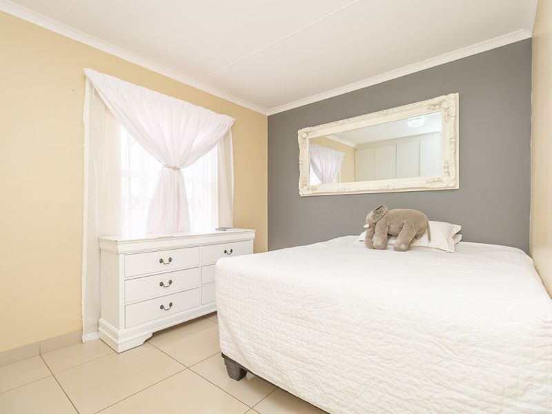 A well-maintained bedroom featuring neutral wall tones, tiled flooring, and built-in storage cupboards.