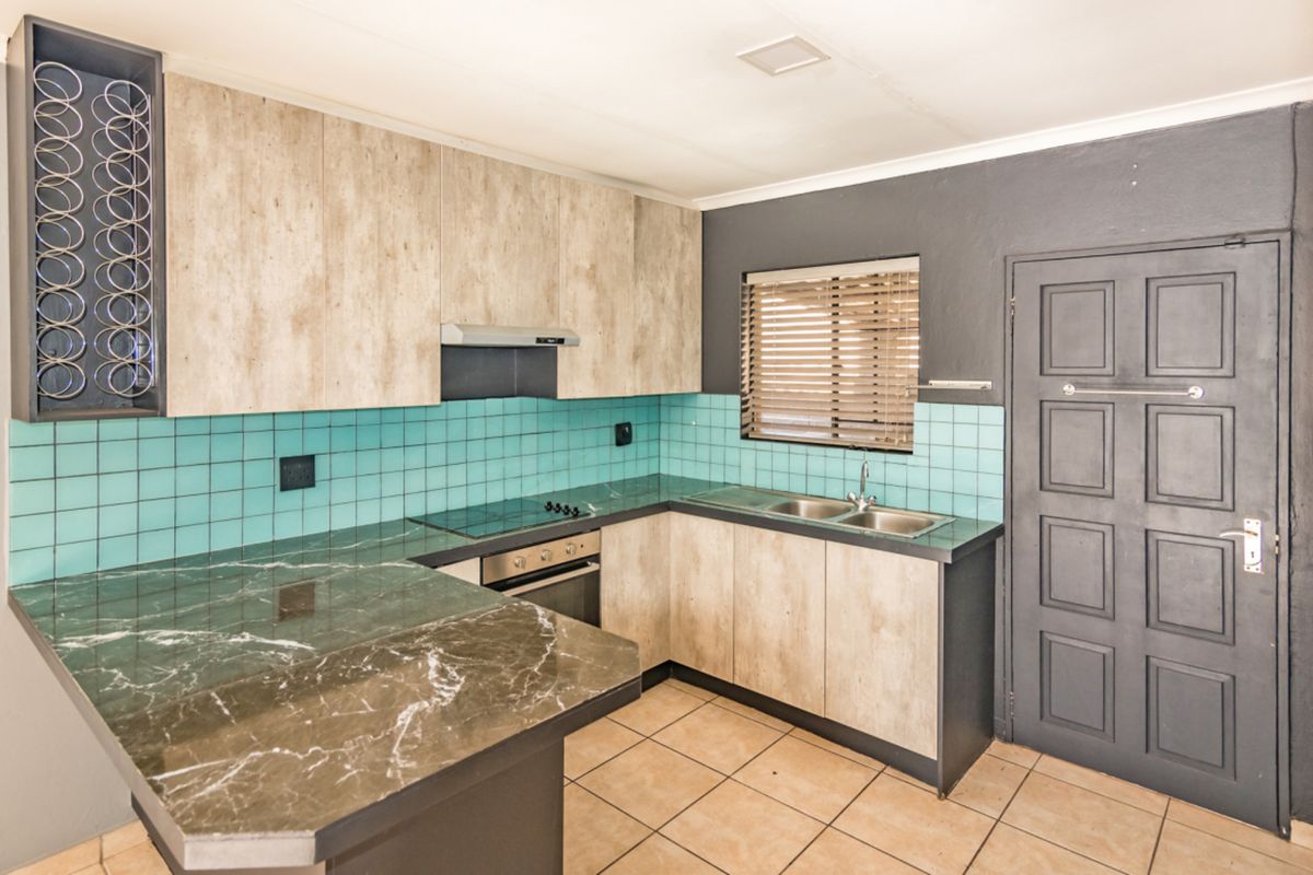 A functional kitchen featuring built-in cabinetry, laminate countertops, a double basin sink, and integrated cooking appliances with a tiled backsplash.