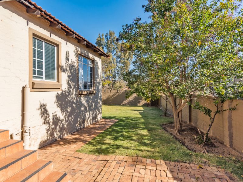 A private rear garden featuring a brick-paved patio area, tiled steps leading to the home, and a secure perimeter boundary wall.