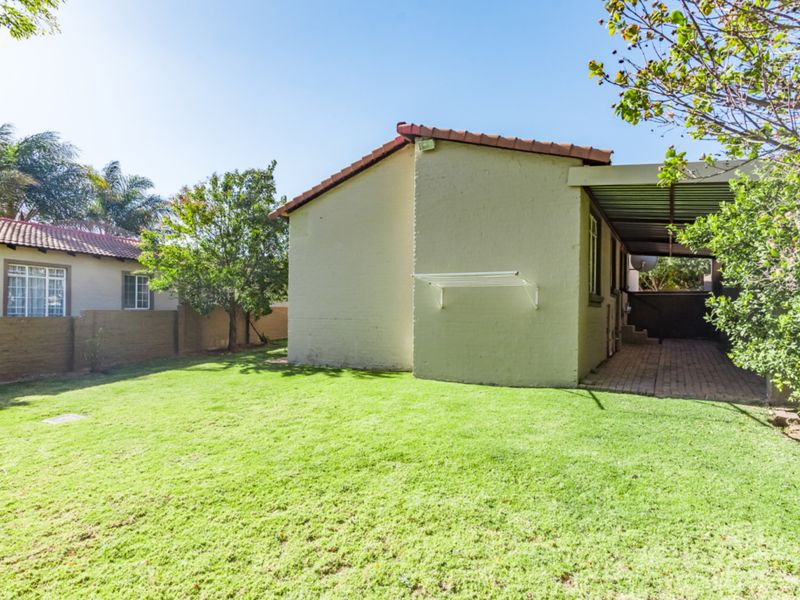 Rear view of the townhouse featuring a private garden, a paved covered patio area, and a wall-mounted drying rack.