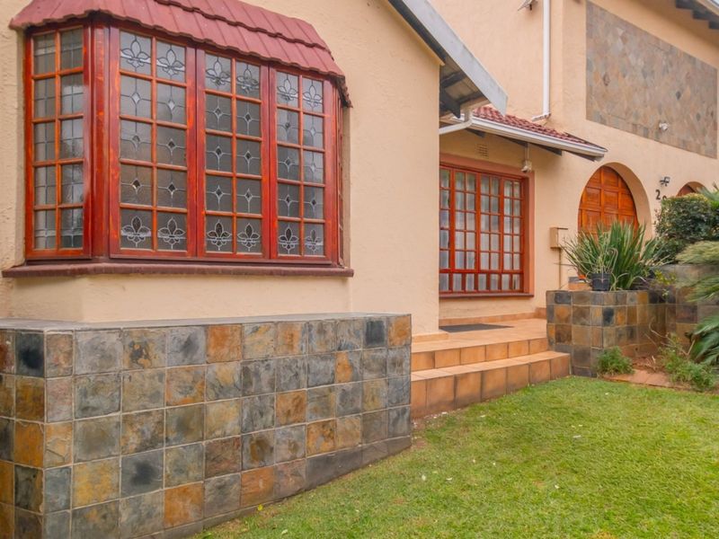 Front facade of the house featuring a bay window, slate stone cladding, and timber-framed windows with a tiled roof.