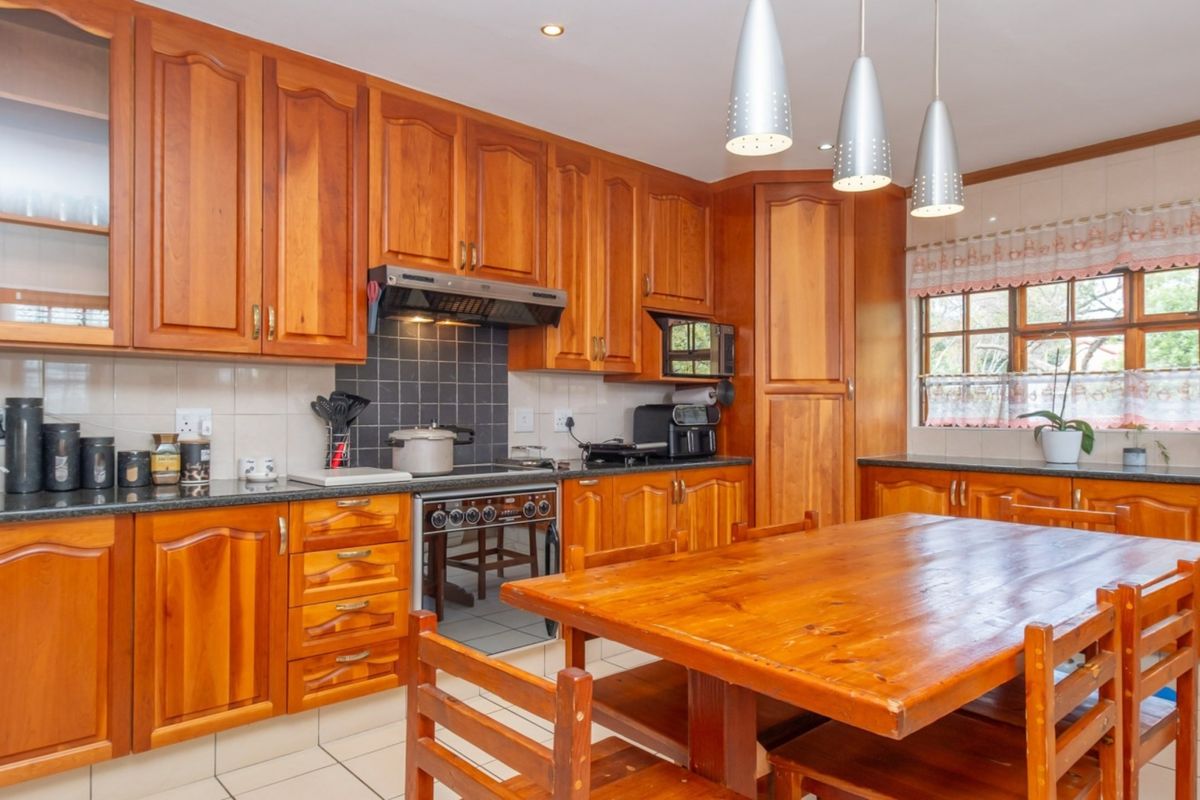 A traditional kitchen featuring warm wooden cabinetry, granite countertops, built-in oven with extractor fan, and tiled flooring, offering a functional and classic cooking space.