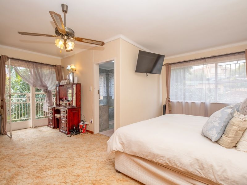 Spacious bedroom featuring an en-suite bathroom, ceiling fan, and direct access to a private balcony through glass doors.