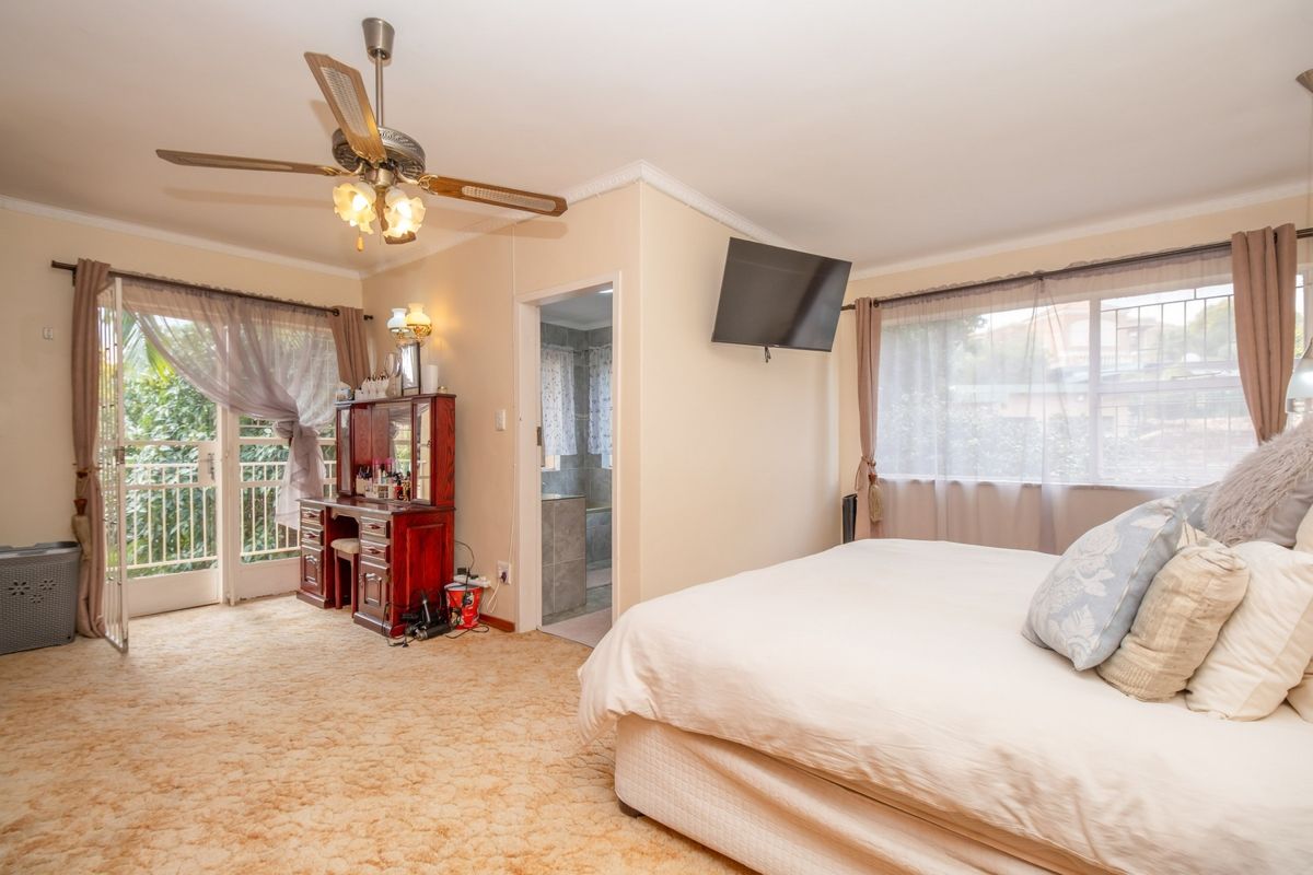 Spacious bedroom featuring an en-suite bathroom, ceiling fan, and direct access to a private balcony through glass doors.
