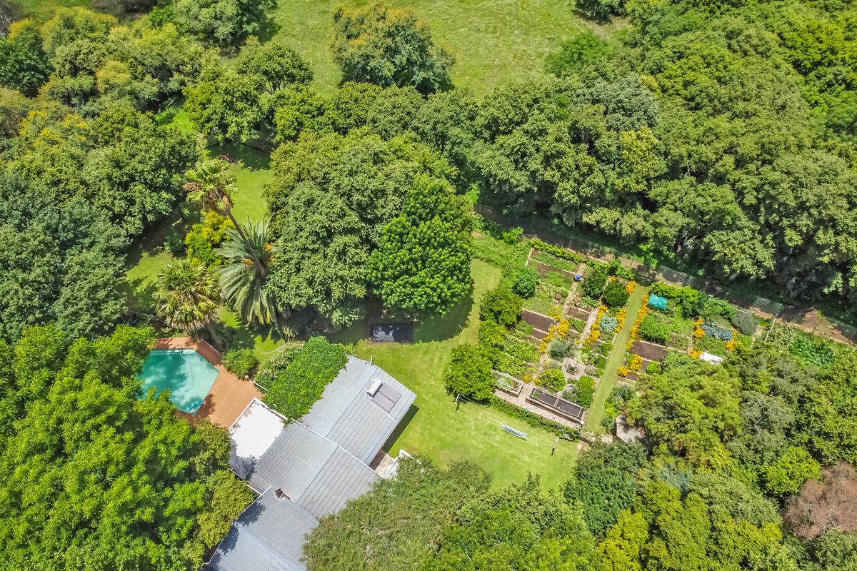 Aerial view of the farm property featuring a swimming pool, metal roof with solar heating, and an extensive established vegetable garden.