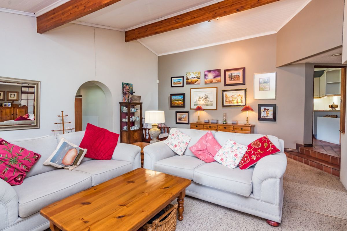 Spacious living room featuring vaulted ceilings with exposed timber beams, an arched doorway, and a tiled step leading to an adjacent area.