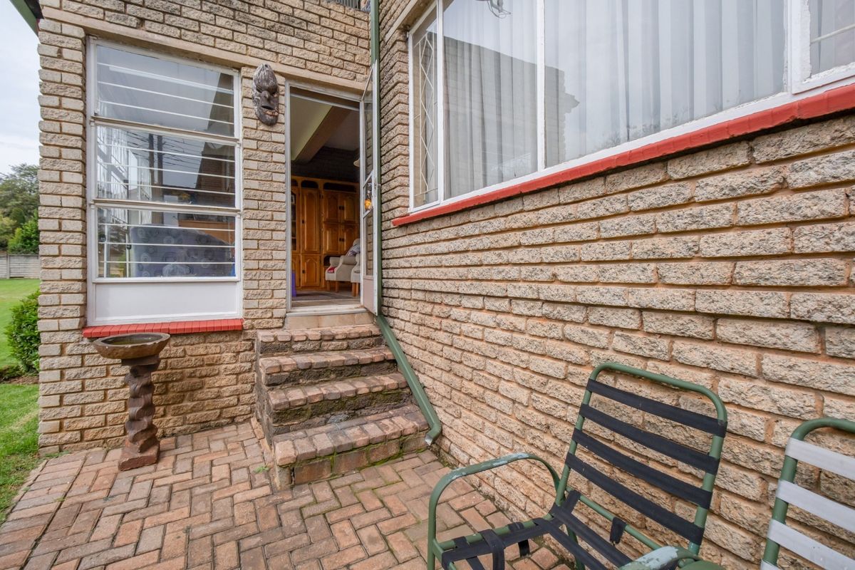 Rear exterior view of the apartment featuring a brick-paved patio area, brick facade, and access steps leading into the interior.