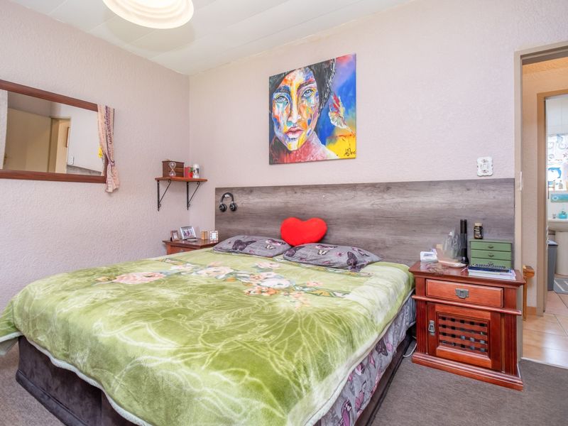 A bedroom featuring a built-in headboard and textured walls, with an adjoining bathroom visible through the doorway.