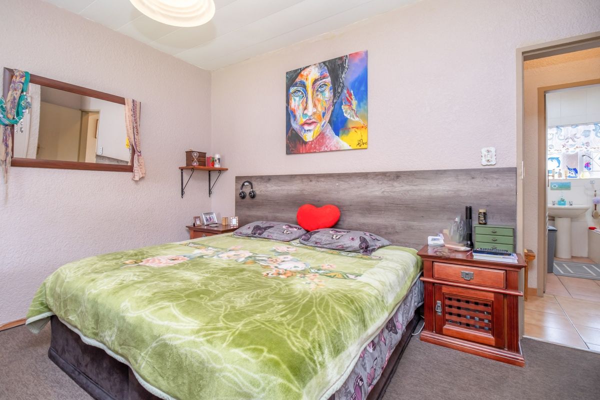 A bedroom featuring a built-in headboard and textured walls, with an adjoining bathroom visible through the doorway.