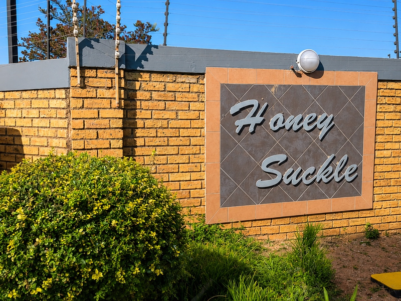 The entrance to Honey Suckle complex featuring a brick boundary wall with integrated signage and security electric fencing.