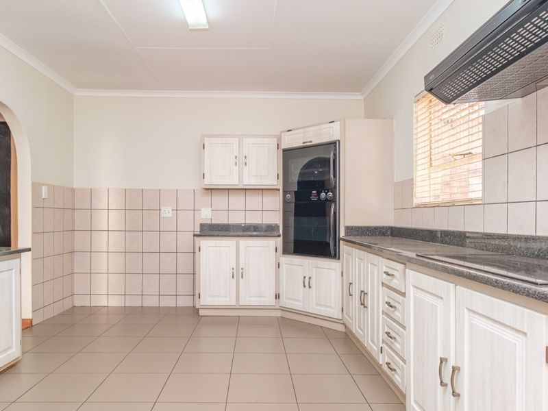 A functional kitchen featuring light-toned cabinetry, granite countertops, tiled backsplash, and built-in appliances including an oven and extractor fan.