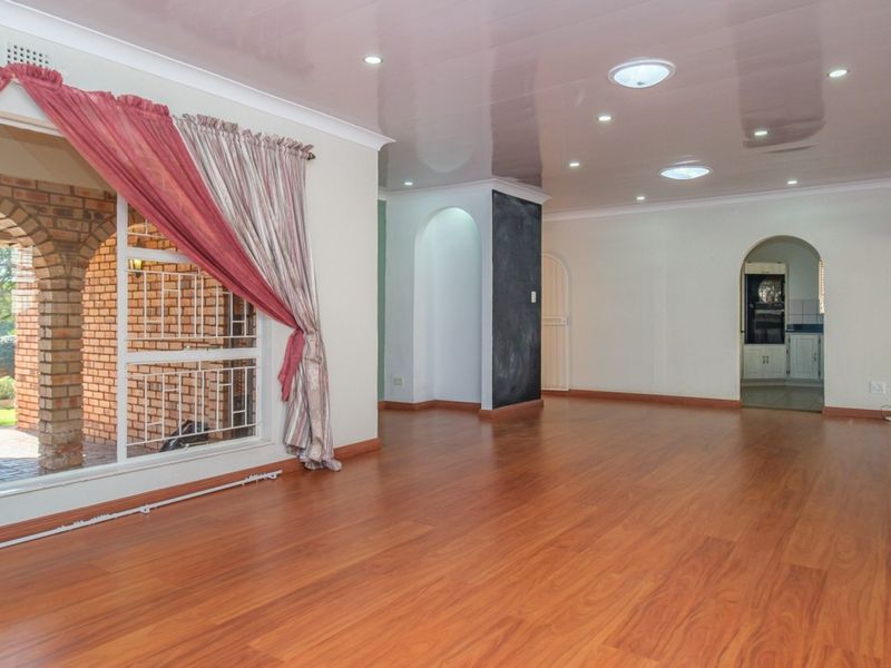 Spacious living area featuring laminate flooring, recessed lighting, and skylights, with an open archway leading to the kitchen area.