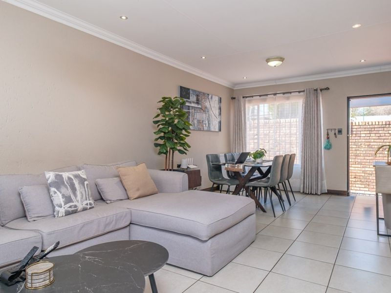 An open-plan living and dining area featuring neutral wall tones, tiled flooring, and recessed lighting, with direct access to an outdoor patio space.