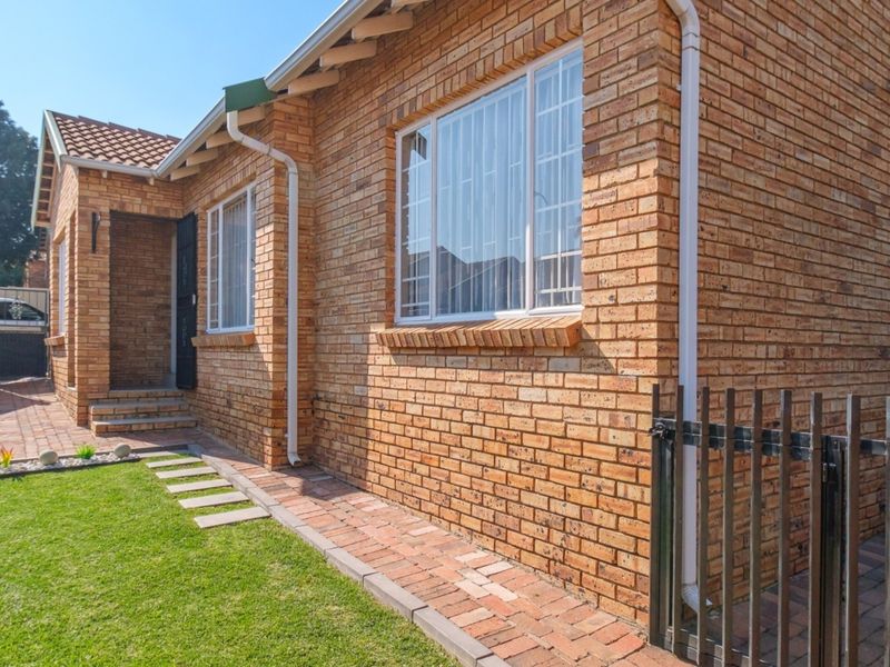 A well-maintained townhouse exterior featuring a classic face brick facade, tiled roof, and a neat brick-paved walkway leading to the entrance.