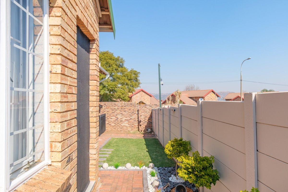 A neat rear garden area featuring a paved walkway, small lawn, and secure perimeter walling, providing a private outdoor space.
