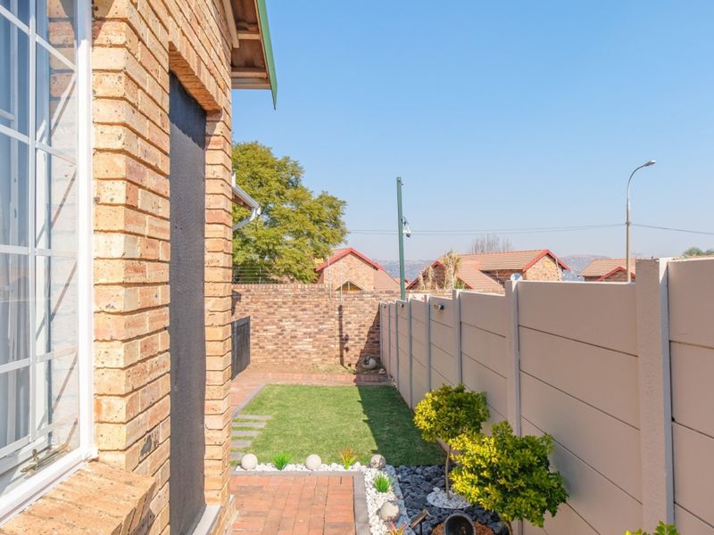 A neat rear garden area featuring a paved walkway, small lawn, and secure perimeter walling, providing a private outdoor space.