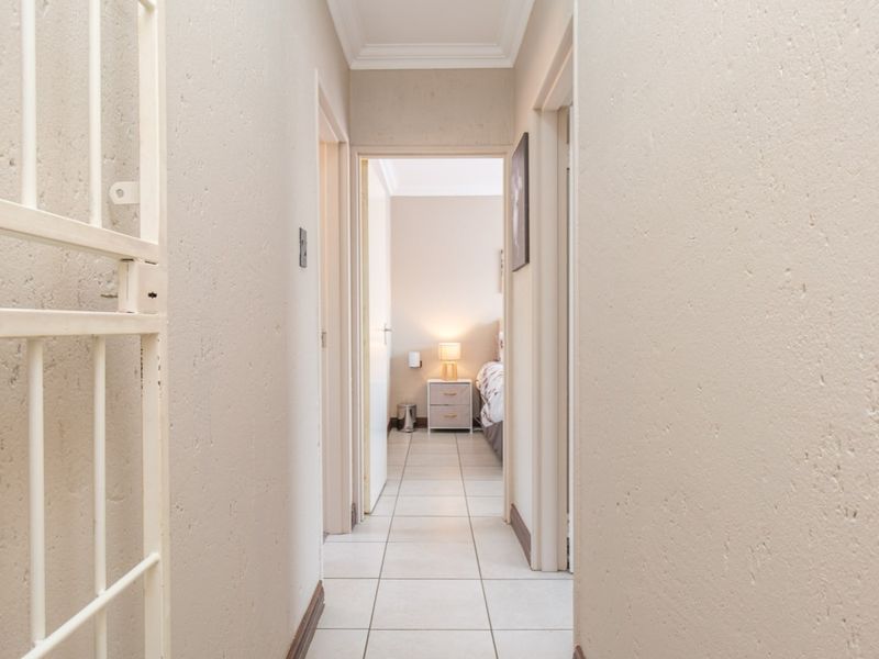 A clean, neutral-toned hallway featuring tiled flooring and decorative cornicing, providing access to adjacent rooms within the townhouse.