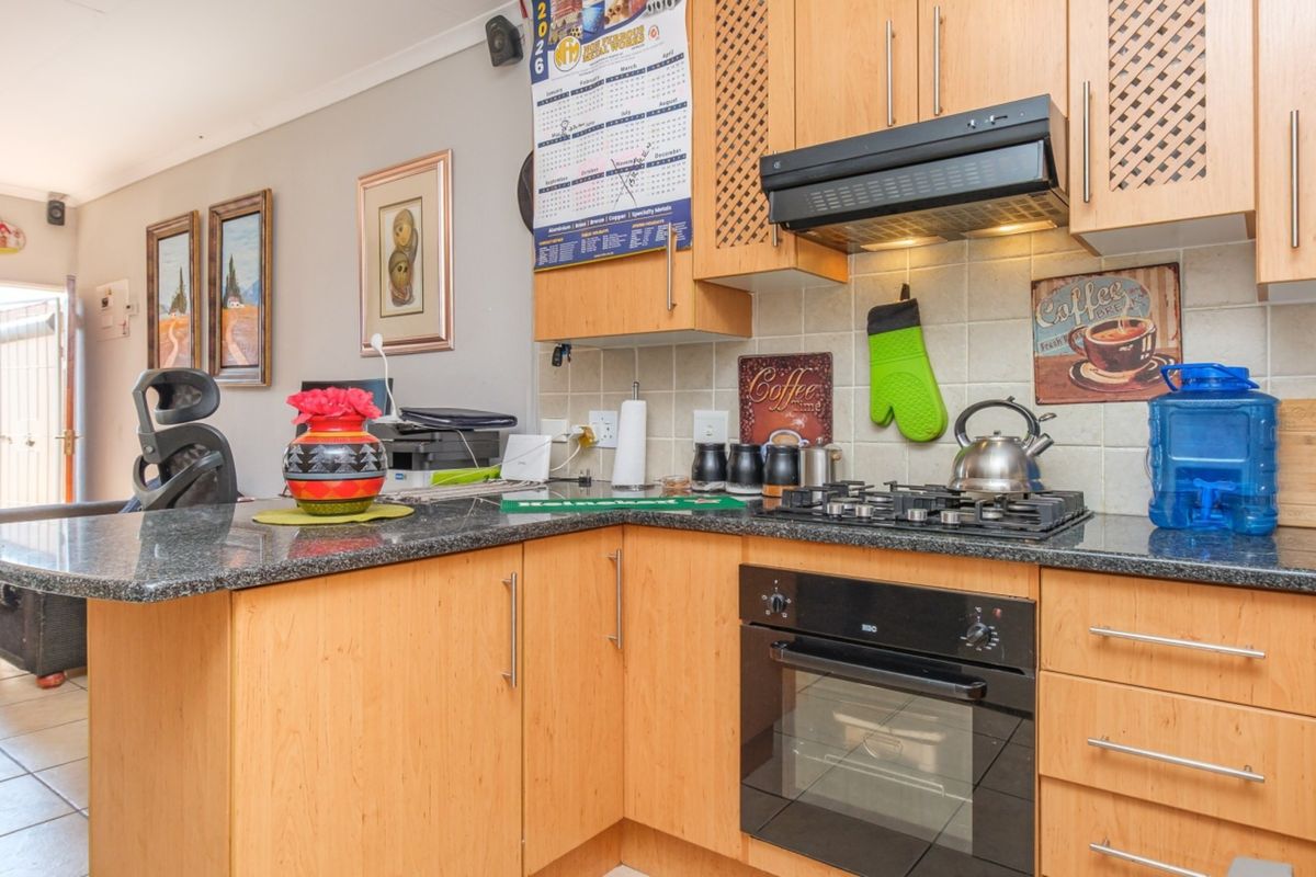 A functional kitchen featuring light wood cabinetry, granite countertops, a gas hob, and a built-in oven with a tiled backsplash.