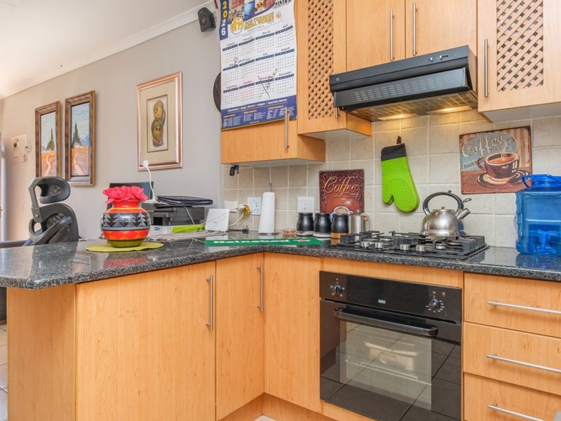 A functional kitchen featuring light wood cabinetry, granite countertops, a gas hob, and a built-in oven with a tiled backsplash.