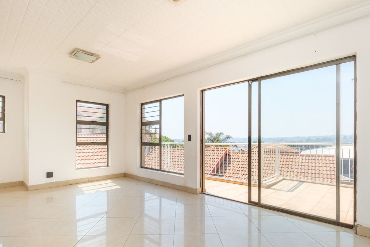 Bright and spacious open-plan living area featuring large windows, tiled floors, and sliding glass doors leading to a private balcony.