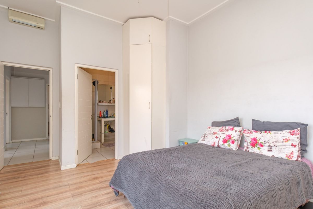 A bedroom featuring laminate flooring, a built-in corner wardrobe, an air conditioning unit, and direct access to an en-suite bathroom.
