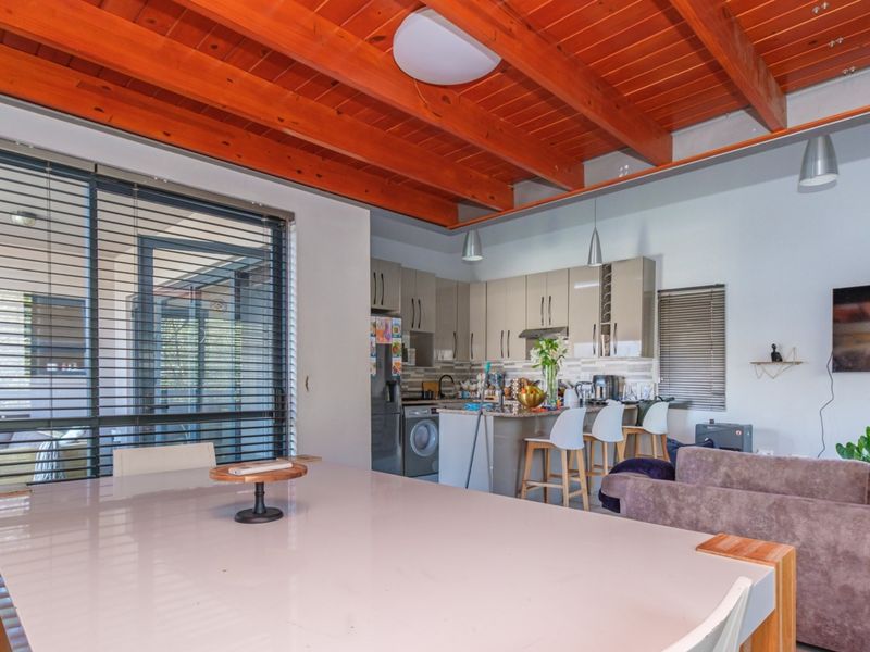 Open-plan living and kitchen area featuring a striking exposed timber beam ceiling, modern cabinetry, and a functional kitchen island with breakfast bar seating.