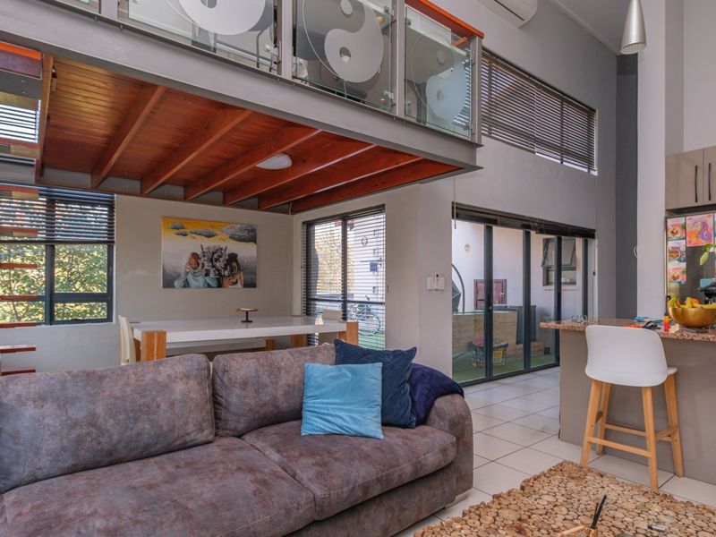 Spacious open-plan living area featuring a mezzanine level, modern kitchen with granite countertops, and large sliding doors leading to an outdoor space.