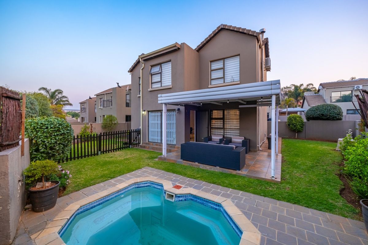 Rear view of the cluster home featuring a private swimming pool, a covered patio area, and a well-maintained garden with perimeter fencing.