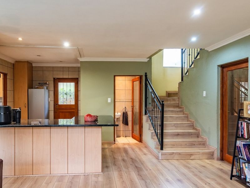 Open plan living area featuring a kitchen island with granite countertop, laminate flooring, and a staircase with wrought iron balustrade.