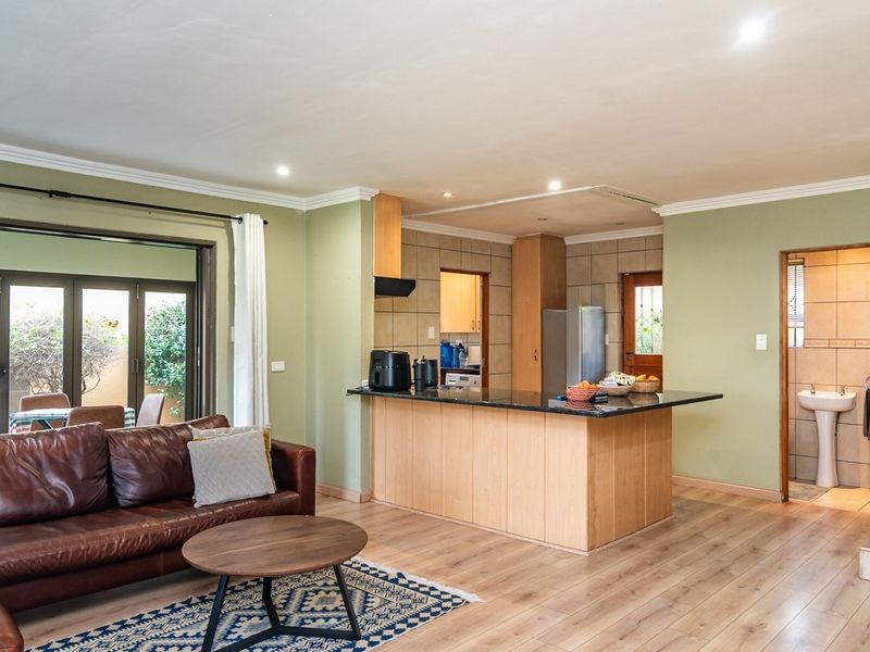 Open plan living area featuring a kitchen island with granite countertops, laminate flooring, and direct access to an outdoor patio through sliding glass doors.