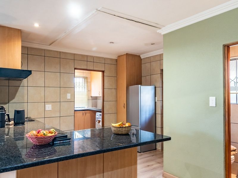 Kitchen featuring granite countertops, tiled backsplash, and built-in cabinetry, with an adjacent bathroom area visible through the doorway.