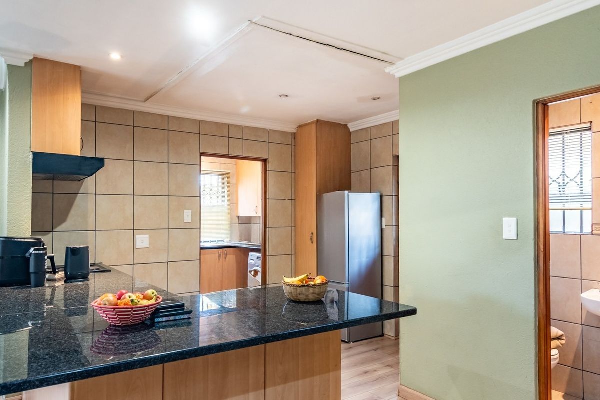 Kitchen featuring granite countertops, tiled backsplash, and built-in cabinetry, with an adjacent bathroom area visible through the doorway.