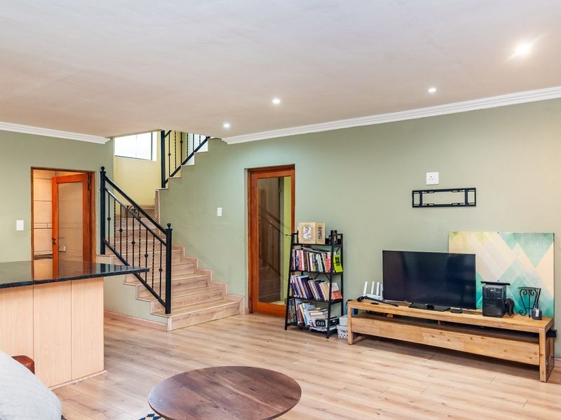 Open plan living area featuring laminate flooring, recessed lighting, and a staircase with a decorative wrought iron balustrade.