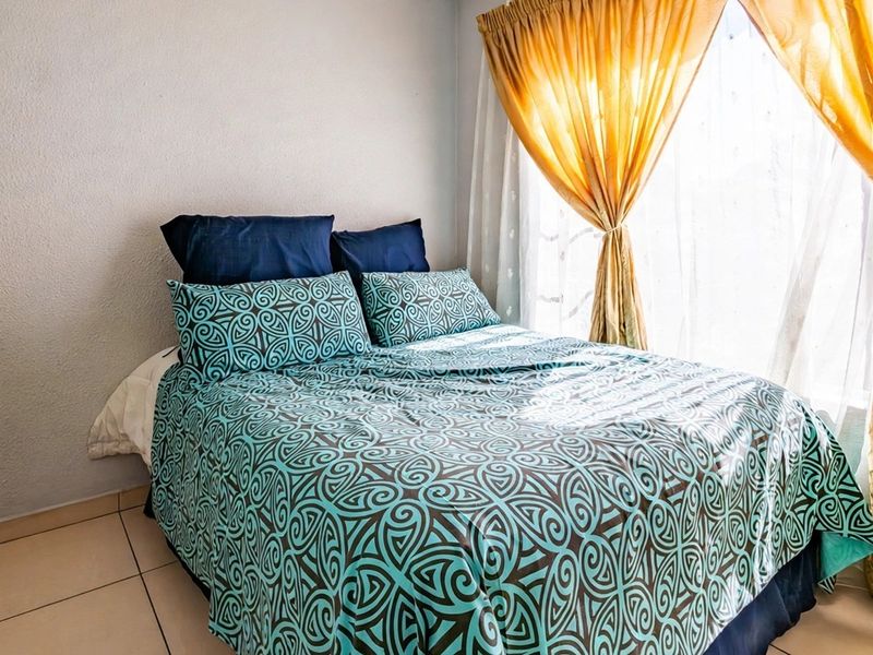 A bedroom featuring tiled flooring and natural light provided by a window with installed curtain rails.