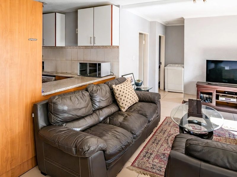 Open-plan living area featuring a functional kitchen with built-in cabinetry, stone countertops, and tiled flooring, seamlessly connected to the lounge space.