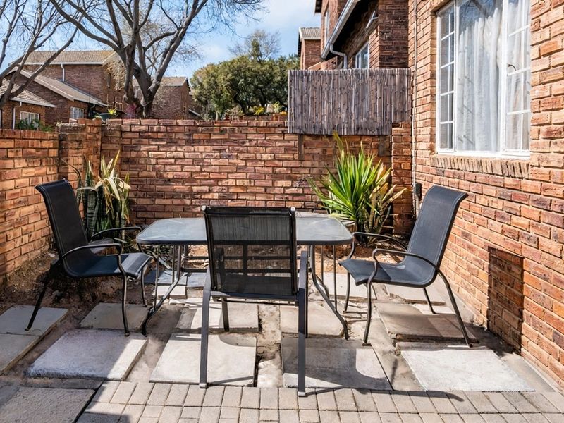 A private outdoor patio area featuring exposed brick walls and paved flooring, providing a functional space for outdoor seating.