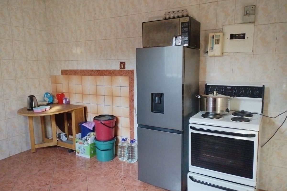 A functional kitchen area featuring tiled walls and flooring, equipped with a freestanding stove and integrated electrical distribution board.