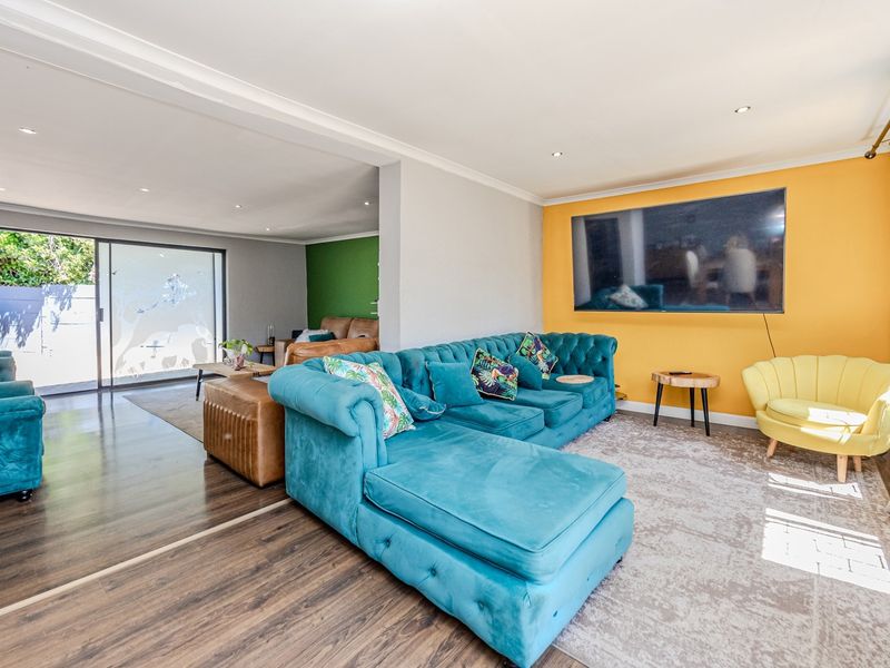 Spacious open-plan living area featuring laminate flooring, recessed downlighting, and a large sliding glass door providing access to the outdoor space.