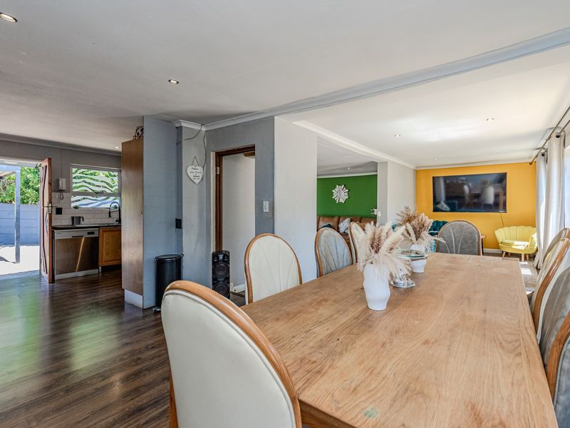Spacious open-plan living and dining area featuring laminate flooring, recessed lighting, and seamless flow to the kitchen and outdoor patio.